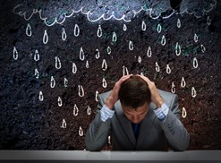 A man sits under fake rain from a fake rain cloud